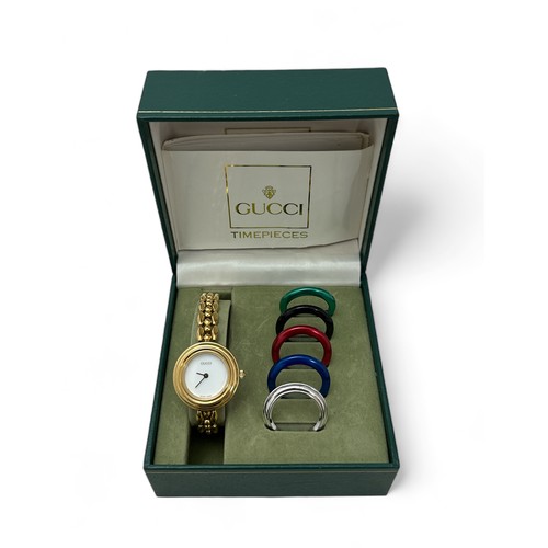 74 - Gucci gold plated lady's bangle wristwatch with five interchangeable coloured ring bezels, with box ... 