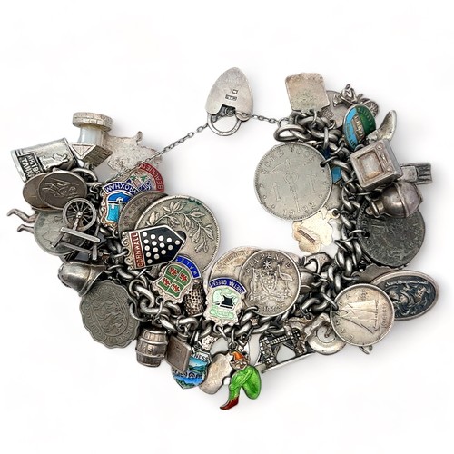 26 - A silver charm bracelet with numerous coins, charms and travel charms attached, many hallmarked or s... 