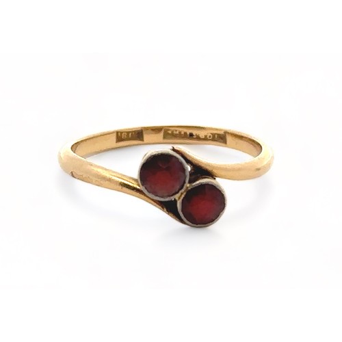 66 - A garnet crossover ring, stamped 18ct, size O. Weight 2.4g

Please see the buyer's terms and conditi... 