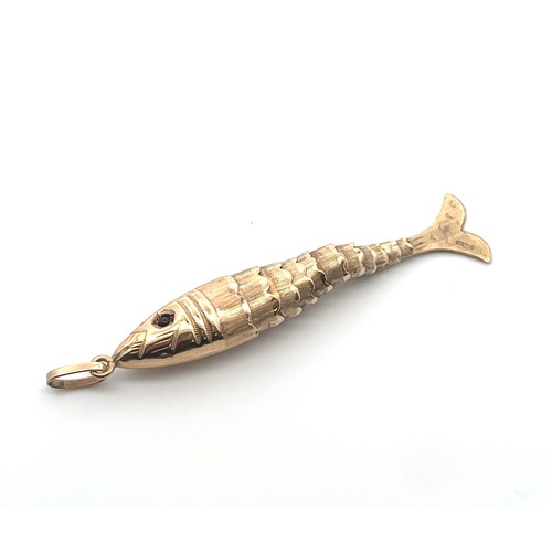 73 - An articulated 9ct gold fish pendant with red gemstone eyes. Stamped 375 on tail. Length 6.5cm inc b... 