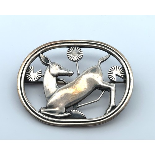 77 - A Georg Jensen Danish oval pierced silver brooch with a deer kneeling amongst foliage. Designed by A... 