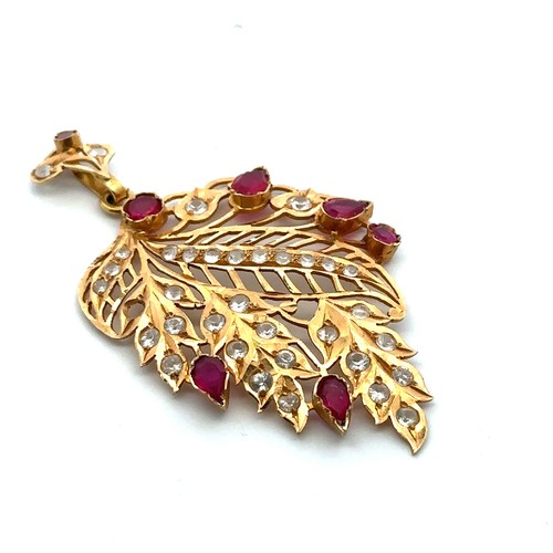 9 - A ruby and white stone (likely topaz) pierced leaf shaped pendant set in unmarked gold, tested using... 