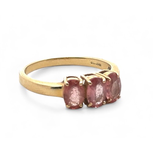 50 - A three stone pink sapphire ring in 18ct yellow gold. Size N. Sapphires each 6mm x 4mm. Hallmarks fo... 