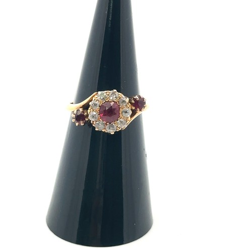 20 - An unusual ruby and old cut diamond cluster ring in a crossover setting and flanked by a ruby on eac... 