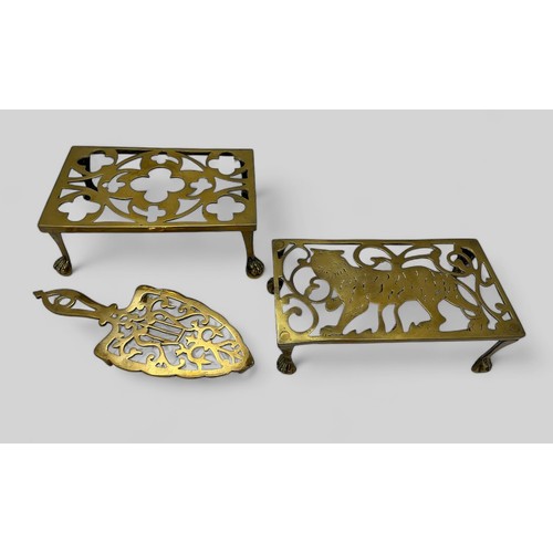 334 - Three vintage /Victorian brass trivets, an iron shaped trivet, a trivet decorated with a tiger, and ... 