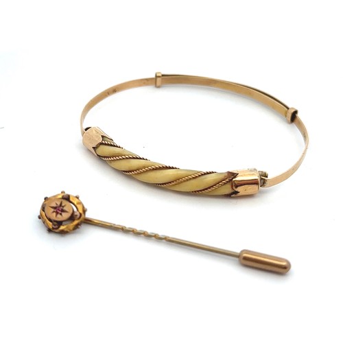 56 - Two jewellery items. An adjustable bangle set with bone in a twisted rope gold surround, stamped 18c... 