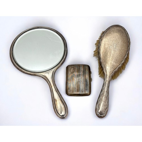 126 - A monogrammed silver backed mirror and dressing table brush, and a cigarette case with engine turned... 