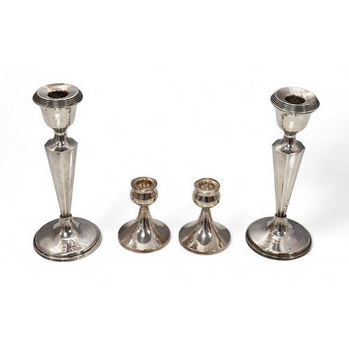 99 - Two pairs of silver candlesticks.  A pair of 21.5cm high candlesticks of octagonal form with weighte... 