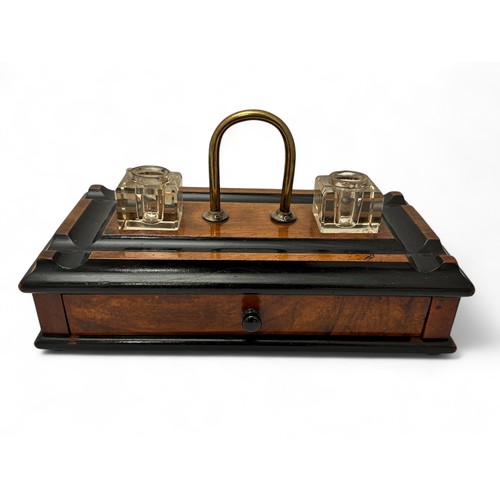 336 - An early 20th Century wooden ink stand with two glass inkwells, a drawer, a brass handle and on four... 