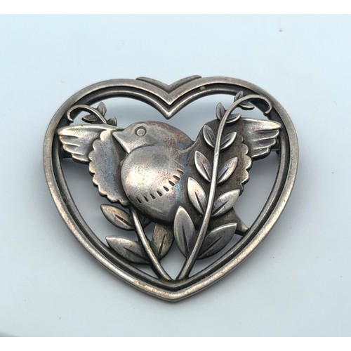 41 - A Georg Jensen silver heart shaped brooch depicting a bird amongst foliage, designed by Arno Malinow... 