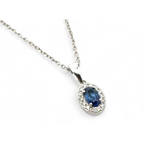 74 - An oval sapphire and diamond cluster pendant set in white gold, stamped 18k, on a 16