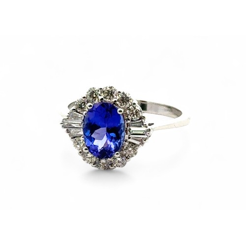 49 - A stunning tanzanite and diamond cluster ring, size N. The oval tanzanite of 1.54ct is surrounded by... 