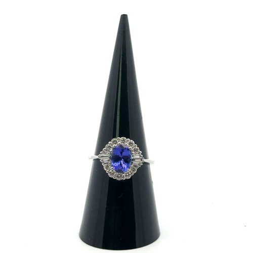 49 - A stunning tanzanite and diamond cluster ring, size N. The oval tanzanite of 1.54ct is surrounded by... 