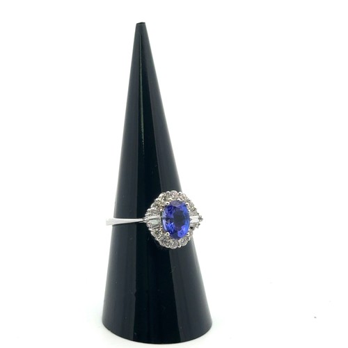 49 - A stunning tanzanite and diamond cluster ring, size N. The oval tanzanite of 1.54ct is surrounded by... 