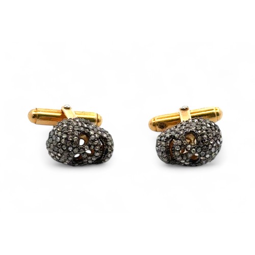 10 - A pair of Memento Mori style silver gilt skull cufflinks set with an estimated 1.80 carats of rose c... 