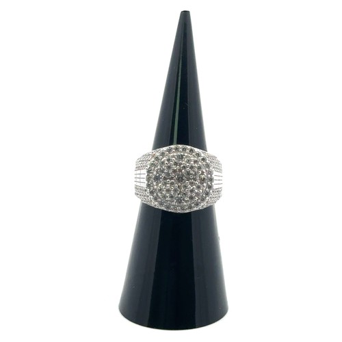 101 - A silver dinner ring heavily set with white round cubic zirconias, size J/K.