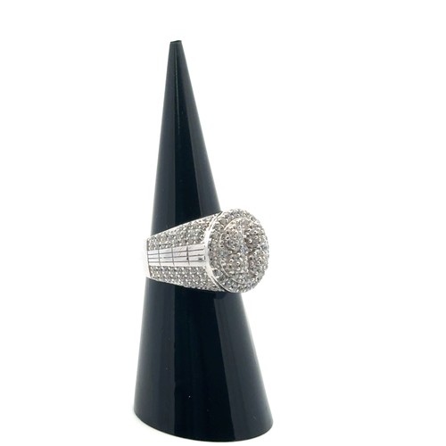 101 - A silver dinner ring heavily set with white round cubic zirconias, size J/K.