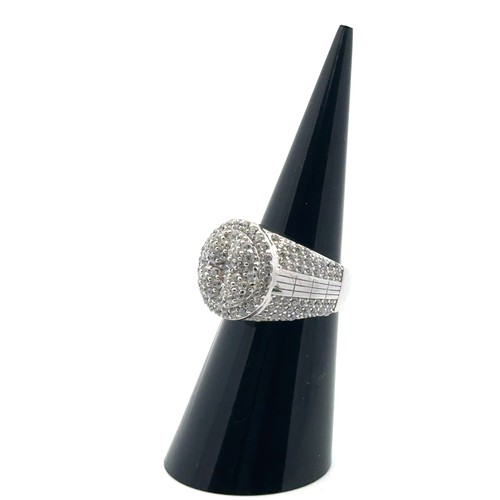 101 - A silver dinner ring heavily set with white round cubic zirconias, size J/K.