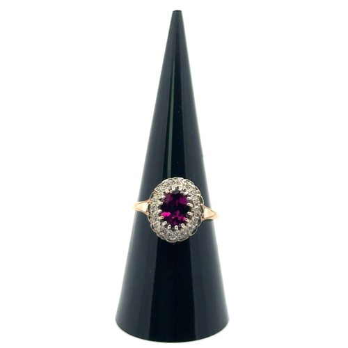 6 - A 9ct yellow and white gold dress ring set with a purplish - red oval rhodonite garnet surrounded by... 