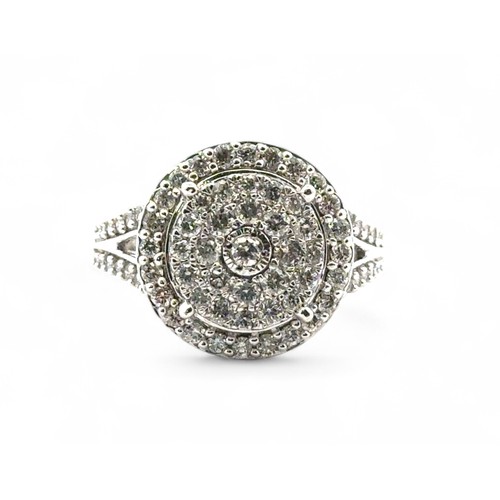 76 - A diamond cluster ring set in 9ct white gold with split shoulders. Inscribed to inner shank as 1ct o... 