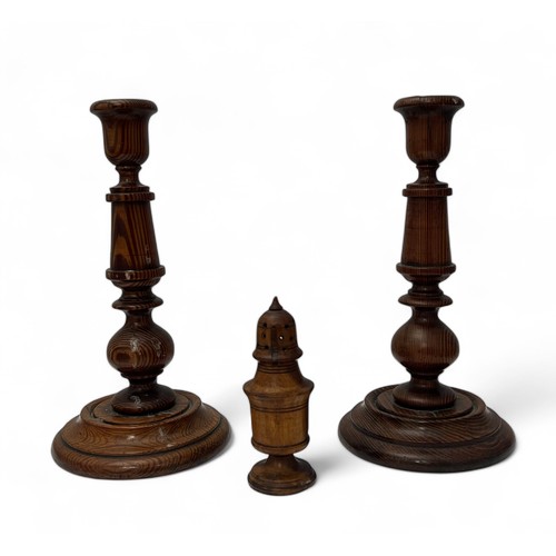 325 - A pair of pitch pine candlesticks (25cm tall) with a treen pepperette of cylindrical pedestal form (... 