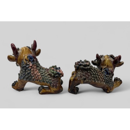 294 - Chinese pottery pair of ferocious Foo Dogs. Unsigned, some chips and damage. Height 17cm. (2)