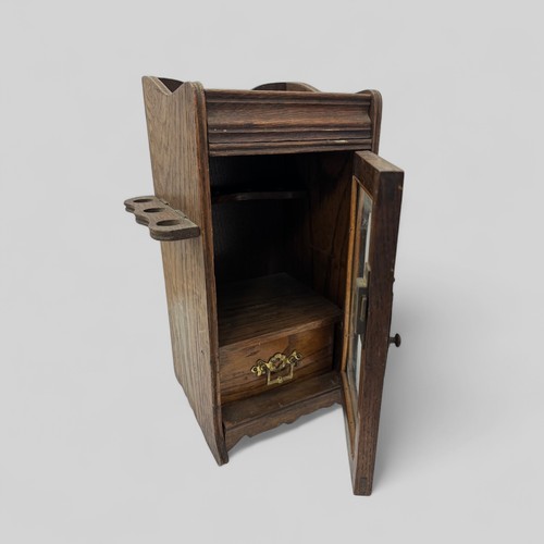 256 - An Oak glass fronted smokers / smoking cabinet with brass fittings. Height 32cm, width 21cm, depth 1... 