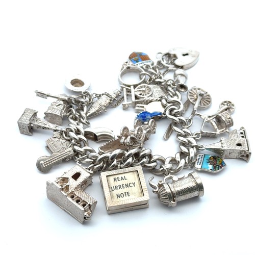 73 - A silver charm bracelet with approx 24 silver and white metal charms. 83g