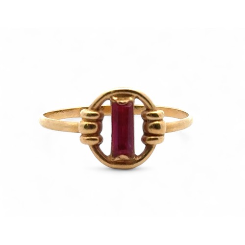 10 - A yellow gold ring with a baguette cut ruby in a circular setting. Unmakred but tests as 18ct using ... 