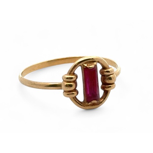 10 - A yellow gold ring with a baguette cut ruby in a circular setting. Unmakred but tests as 18ct using ... 