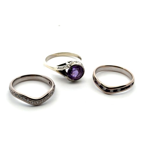 53 - A bespoke set of three rings designed to be worn together. Including an amethyst and diamond cluster... 