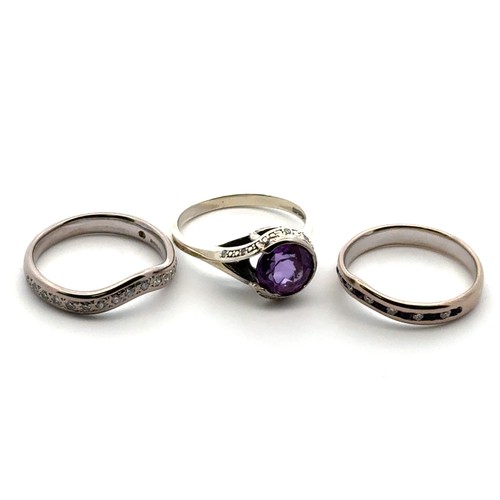 53 - A bespoke set of three rings designed to be worn together. Including an amethyst and diamond cluster... 