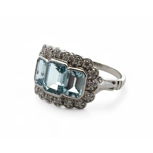 27 - An 18ct white gold aquamarine and diamond ring, size M/N. Set with emerald-cut aquamarines surrounde... 