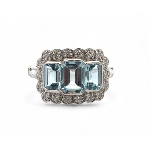 27 - An 18ct white gold aquamarine and diamond ring, size M/N. Set with emerald-cut aquamarines surrounde... 