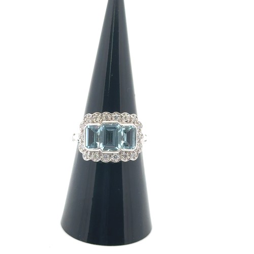 27 - An 18ct white gold aquamarine and diamond ring, size M/N. Set with emerald-cut aquamarines surrounde... 