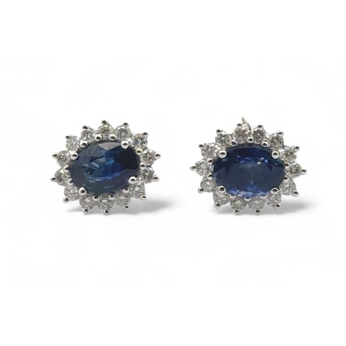 45 - A pair of 18ct white gold oval sapphire and diamond cluster stud earrings.  Sapphires approx 1.9ct, ... 