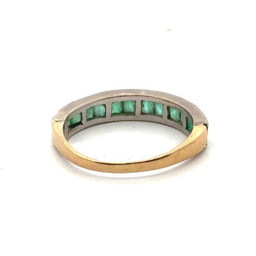 12 - A channel set emerald ring in a yellow metal mount, stamped 18. Size N. 2.95g.