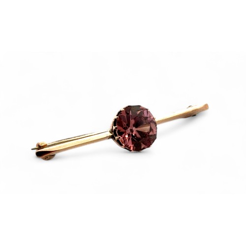 40 - A bar brooch set with a brownish pink zircon, approx 10mm in diameter,  in unmarked yellow metal. Le... 