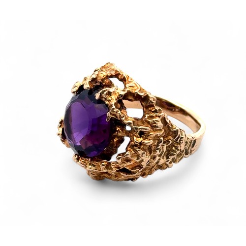 1 - A textured gold ring set with a round step cut amethyst  (12mm diameter), stamped 9ct. Size K. Weigh... 