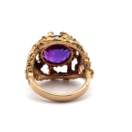 1 - A textured gold ring set with a round step cut amethyst  (12mm diameter), stamped 9ct. Size K. Weigh... 