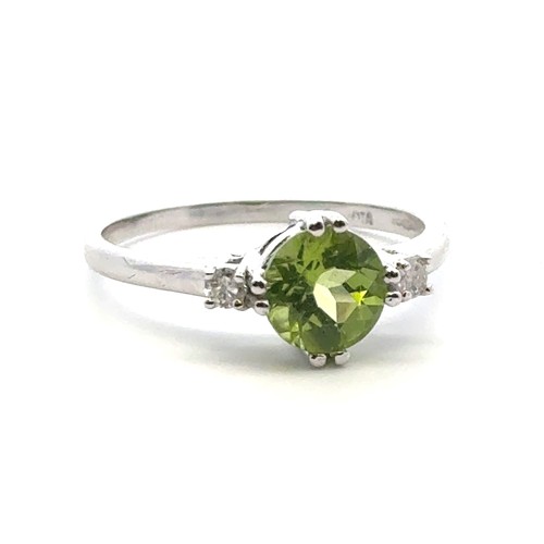 21 - A peridot ring with diamond accents in 9ct white gold. Size R.