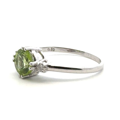 21 - A peridot ring with diamond accents in 9ct white gold. Size R.