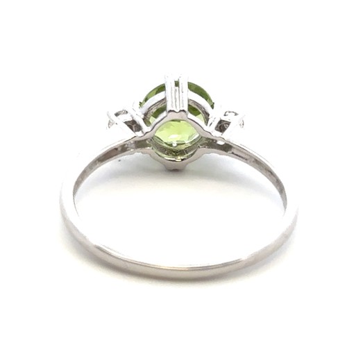 21 - A peridot ring with diamond accents in 9ct white gold. Size R.