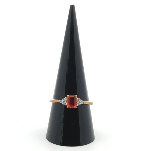 22 - An orange stone ring with diamond accents in 9ct gold, size R.