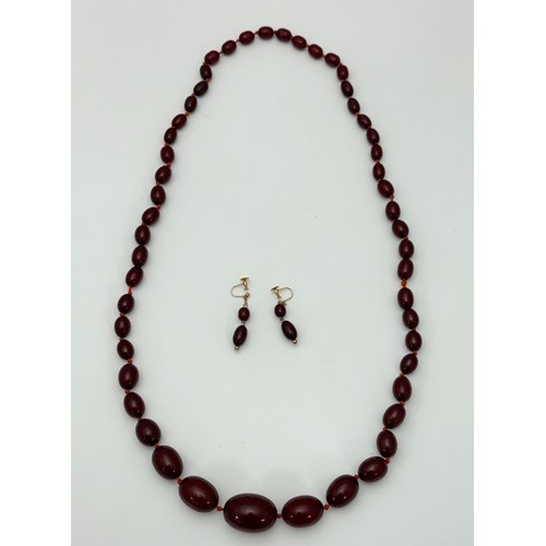 13 - A cherry amber/ bakelite bead necklace and earrings.  Necklace comprises of 51 beads, largest bead a... 