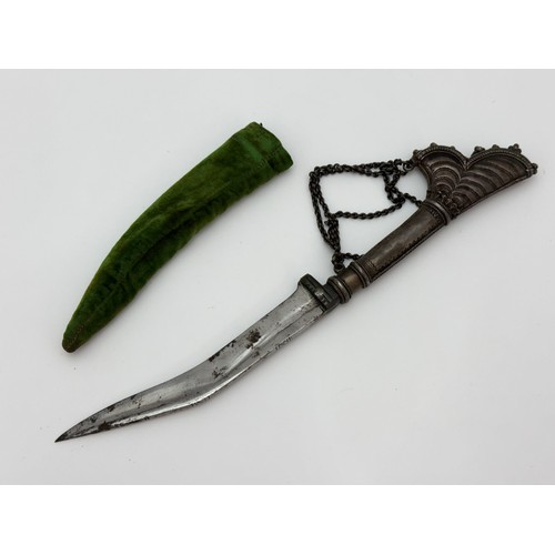 38 - White metal curved Middle Eastern dagger in sheaf. Blade length 16cm, overall length 32cm.