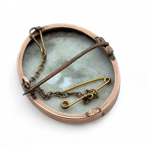 56 - A brooch set with a painted porcelain portrait of a young girl, mount stamped 15ct. length 36mm.