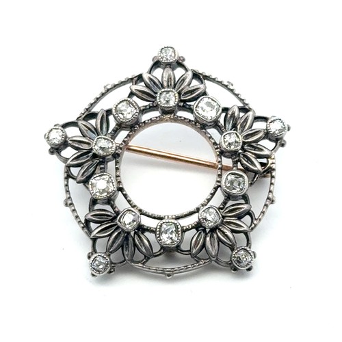 14 - A Victorian diamond brooch in a silver on gold open work mount, set with cushion shaped old cut diam... 