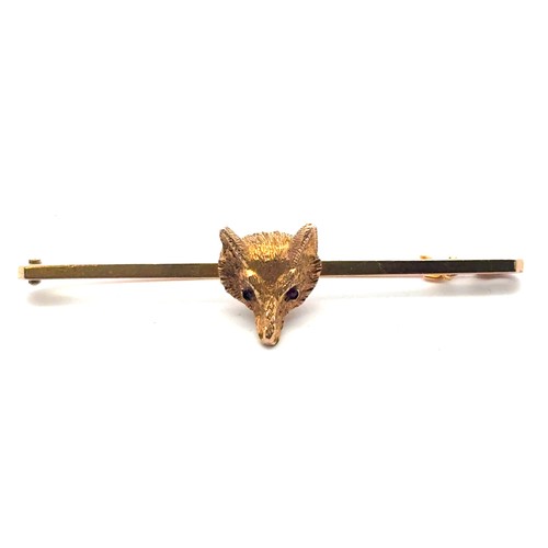 29 - A gold fox head bar brooch with red stone eyes, length 50mm. Pin and bar stamped 9ct, fox head tests... 