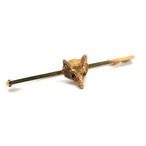 29 - A gold fox head bar brooch with red stone eyes, length 50mm. Pin and bar stamped 9ct, fox head tests... 